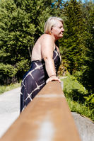 Frau bei einer Portraitsession am Forstsee in Kärnten, umgeben von Wald und Wasser, genießt einen ruhigen Moment in der Natur voller Leichtigkeit, Ausgeglichenheit und Selbstwahrnehmung.