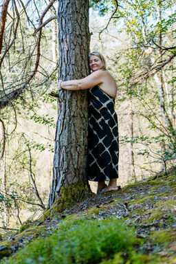 Frau bei einer Portraitsession am Forstsee in Kärnten, umgeben von Wald und Wasser, genießt einen ruhigen Moment in der Natur voller Leichtigkeit, Ausgeglichenheit und Selbstwahrnehmung.