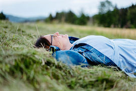 Frau bei einer Fotosession am Maltschacher See in Kärnten, umgeben von Natur mit Getreidefeldern und frisch gemähtem Gras, entspannt im Moment und die Umgebung genießend.