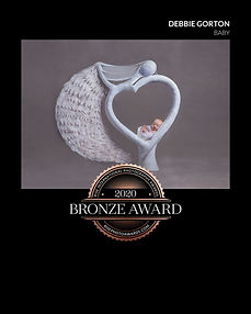 A newborn baby girl in a prop designed by the photographer of a women holding a baby in its arms, it won an award.
