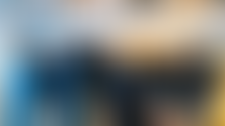 A group of ten people smiling in an office with soft lighting, wearing casual clothing and hoodies. The mood is cheerful and relaxed.