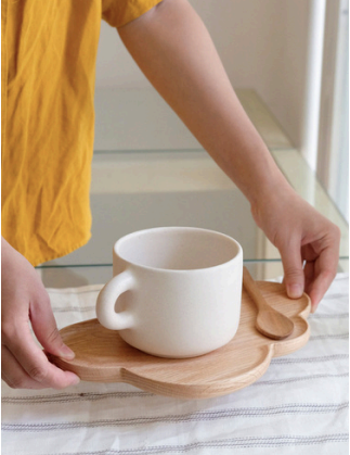 Thumbnail: Woman puts down a maple wood cloud tray with a white cup on it