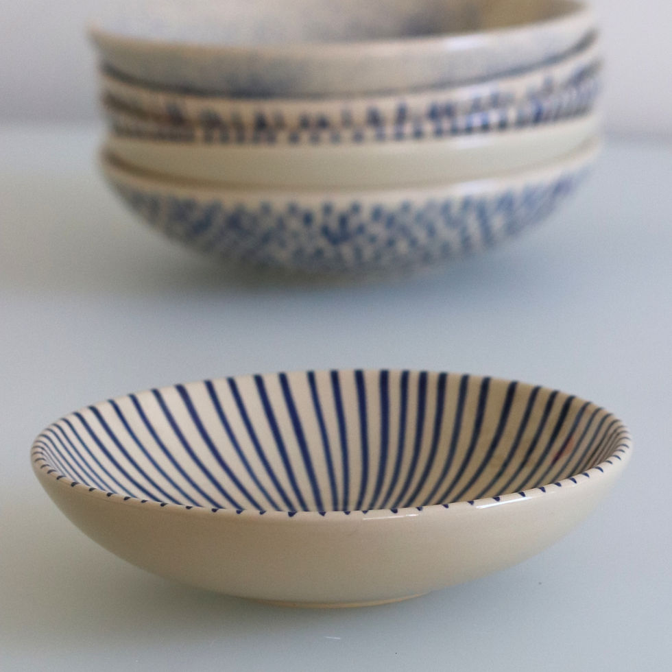 Matrix salad bowl in forefront with stack of other design indigo salad bowls behind it all handpainted in Vietnam