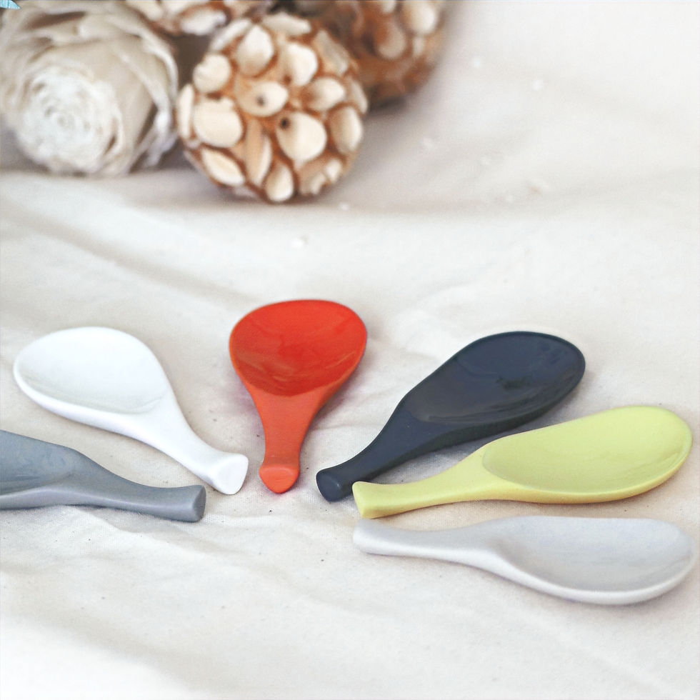 six colourful ceramic spoon rests sit on a cream table cloth