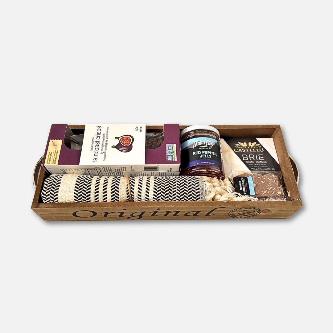 Wooden tray with hands, filled with items locally sourced. Crackers, hand towel, jelly, cheese.& chocolate.
