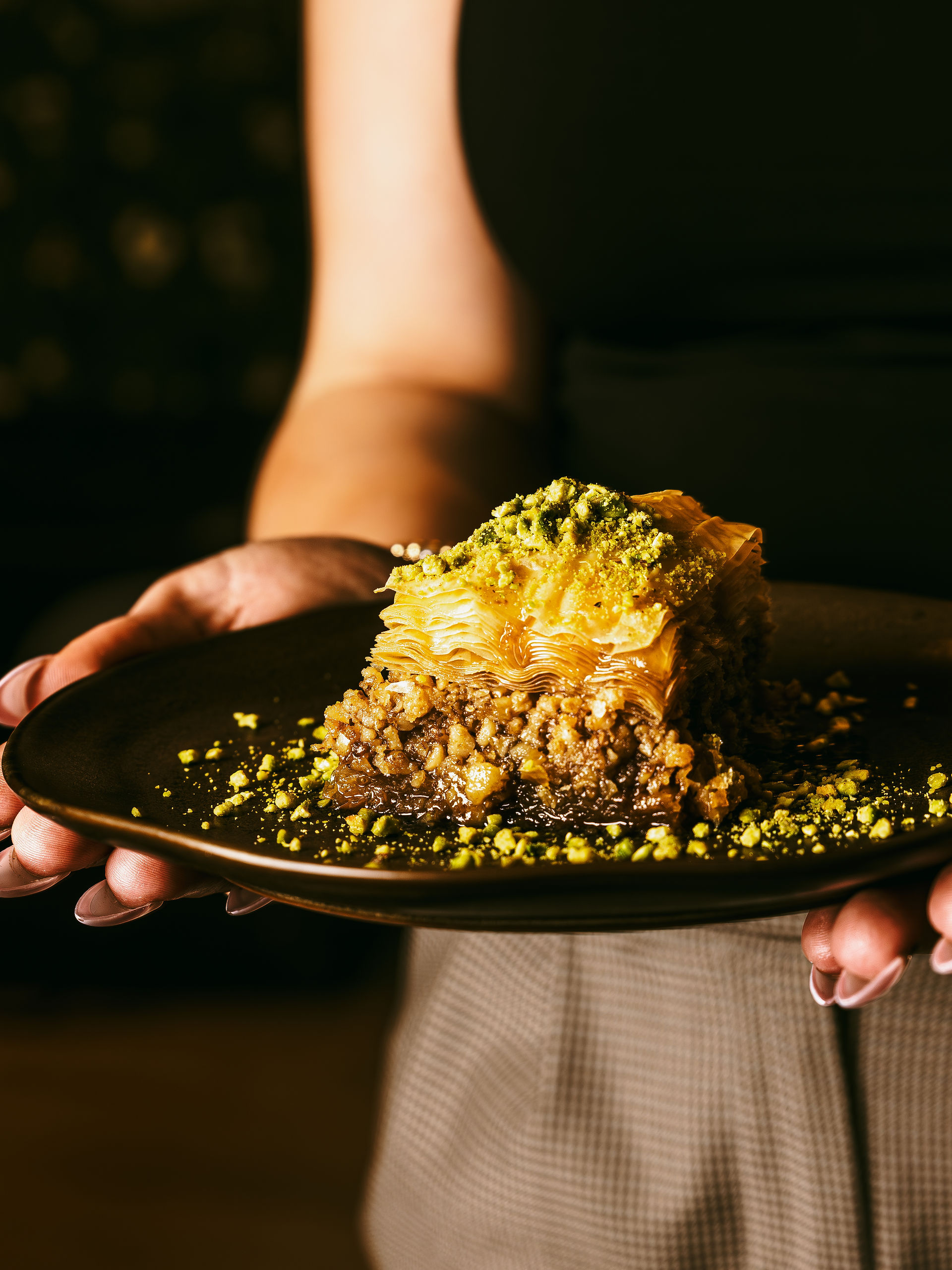 hand holding plate with Baklava dessert