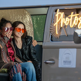 Two women in sunglasses posing in a photo booth van