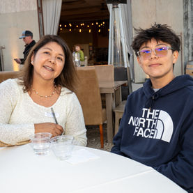 Woman and teenager smiling at an outdoor restaurant table