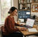 Small business owner reviewing content analytics dashboards on a laptop and monitor in a bright office
