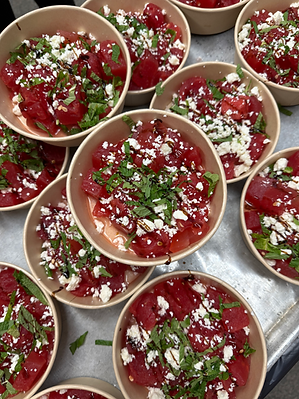 Small bowls of watermelon salad topped with feta cheese, fresh herbs, and balsamic drizzle.