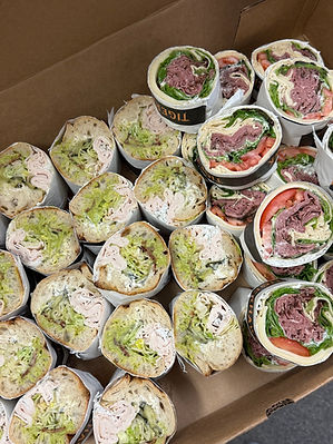 Assorted catering wraps sliced in half and arranged in a tray for serving.