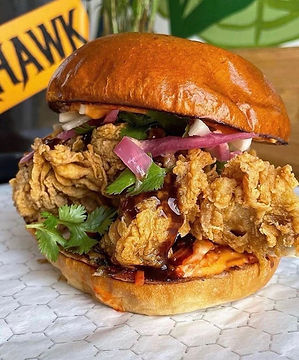Crispy fried chicken sandwich with pickled onions, cilantro, sauce, and a toasted bun.