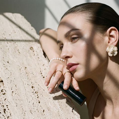Overhead view of a bridal makeup setup with lip oil, creamy lipstick, and earrings