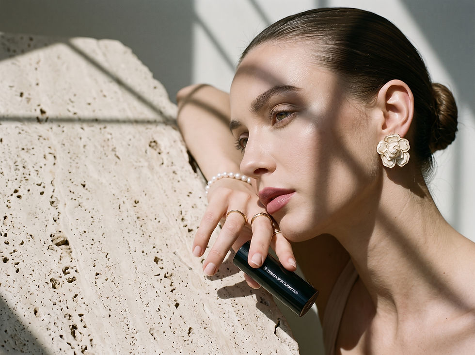 Overhead view of a bridal makeup setup with lip oil, creamy lipstick, and earrings
