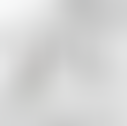 Skincare products on a white marble surface beside a window. Includes bottles, a tube, a leaf, a pebble, and a paper labeled YESHUA SKIN.