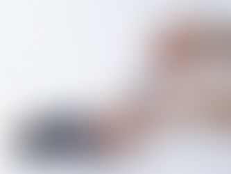 Hands applying dark cream from a jar labeled "Glow Mask" with a spatula on a white tiled background. Calm and clean atmosphere.