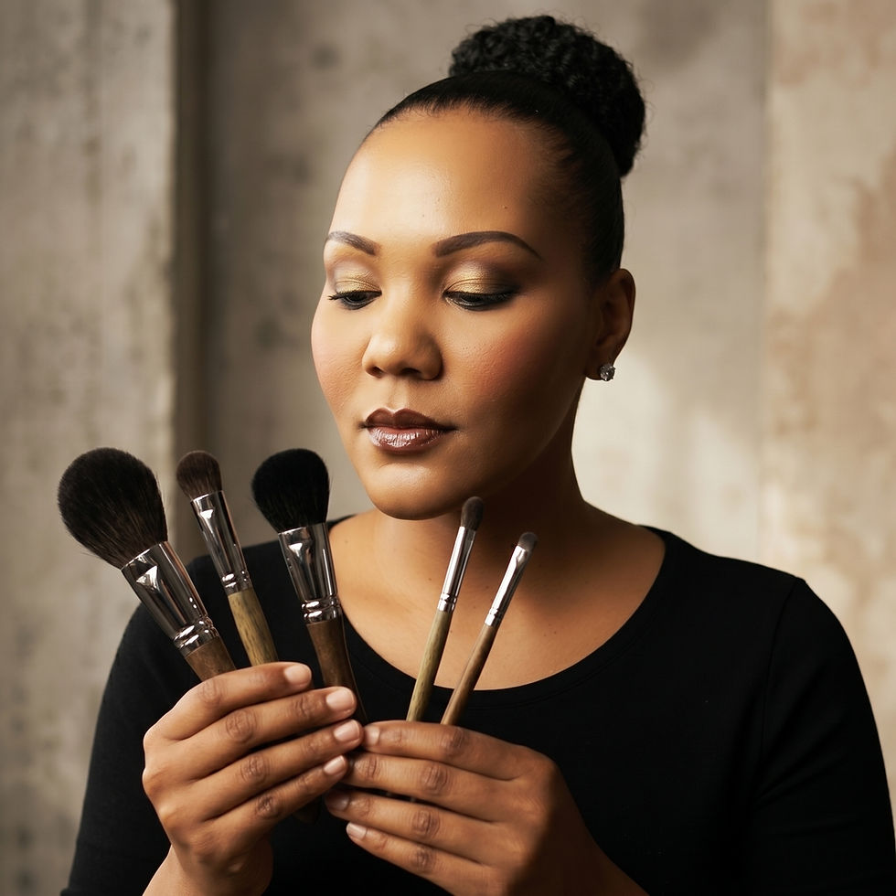 Woman in black top holds five makeup brushes, looking down calmly against a soft beige background.