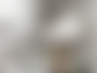 Spa setting with skincare bottles labeled "Yeshua Skin," bowls of herbs, and cucumbers. White massage table in the background. Calm mood.