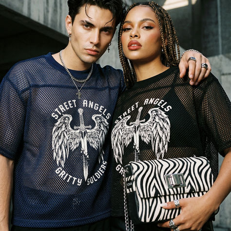 Two people in mesh shirts with "Street Angels" text stand closely. One holds a zebra-patterned bag. Urban backdrop, confident mood.