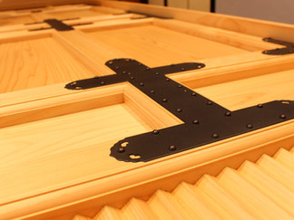 黒色の錺金具（かざりかなぐ）を取り付けた木製扉の製作風景