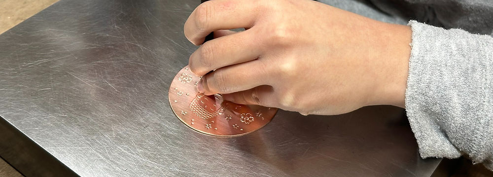 大仏の描かれた銅板の背景に彫金している