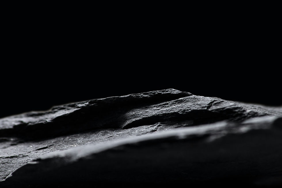 The flint that sparks it all. A dark grey jagged stone on a black background