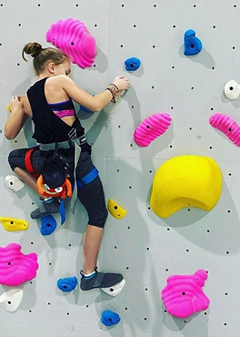 a boy and a girl climbing a white wall with multicolor hand/foot holds