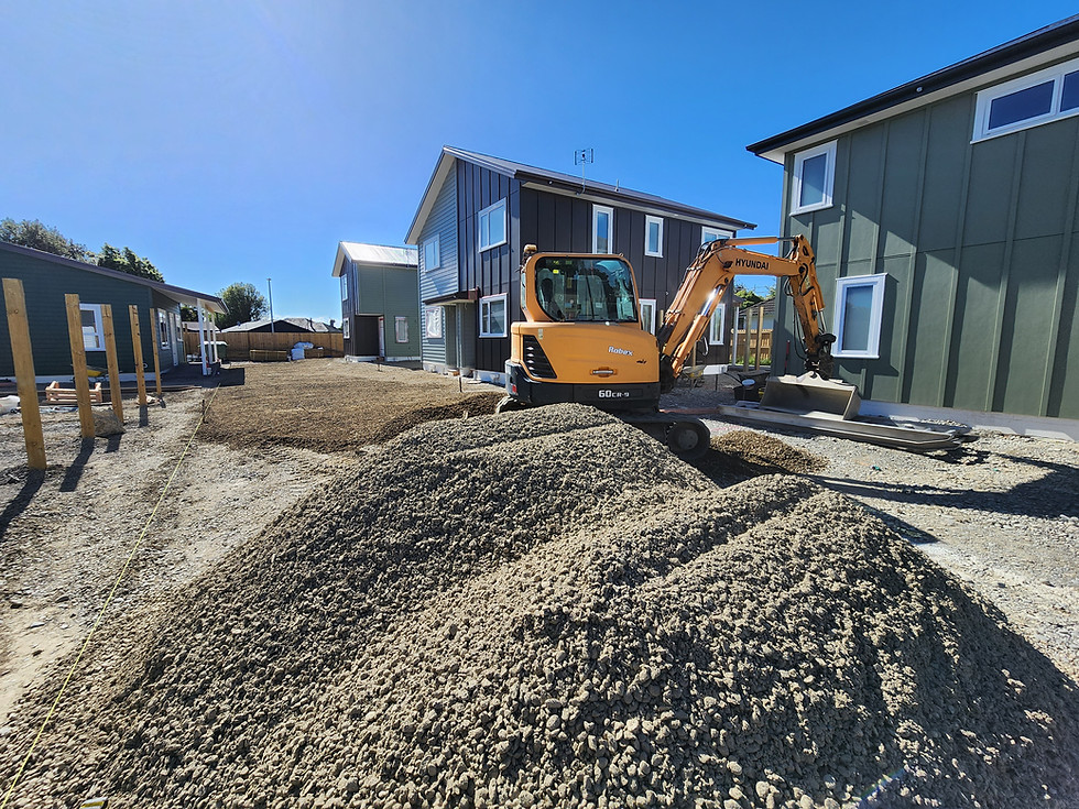 Excavator carrying out residential site preparation beside new homes in Canterbury.