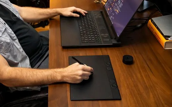 Man working on laptop with Wacom tablet
