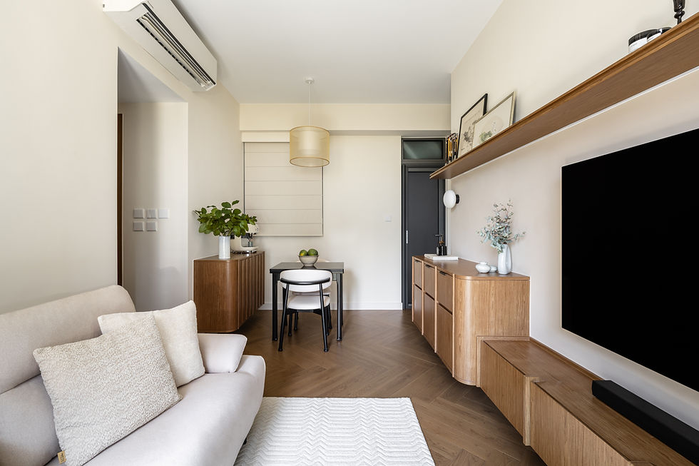Modern living room with beige sofa, wooden furniture, and chevron rug. Black TV, plants, and art on shelves. Bright, minimalist aesthetic.