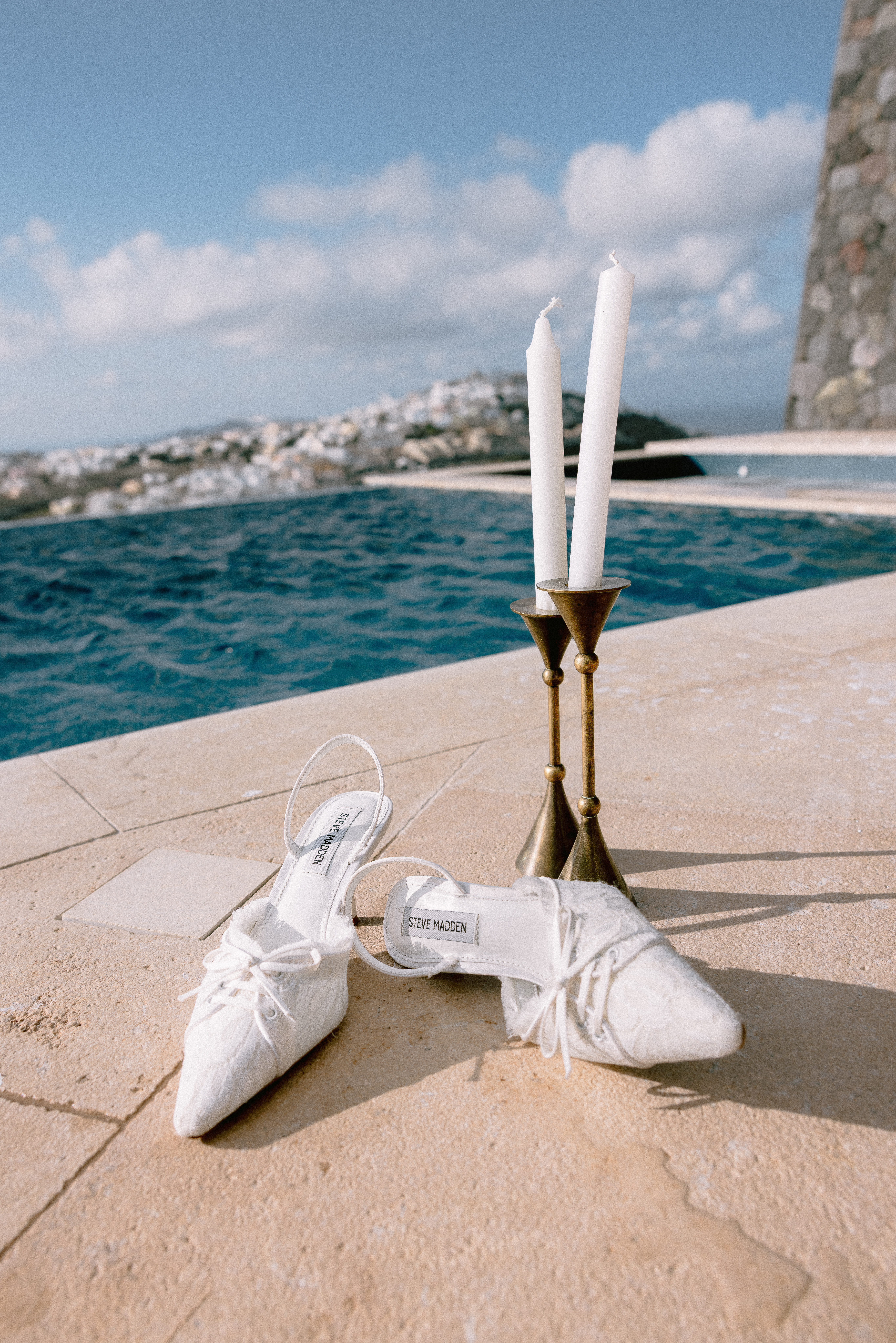 Bridal shoes and wedding details beside an infinity pool overlooking the Mediterranean.