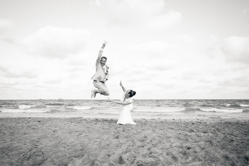 Bräutigam springt vor Freude in die Luft am Strand von Ibiza.