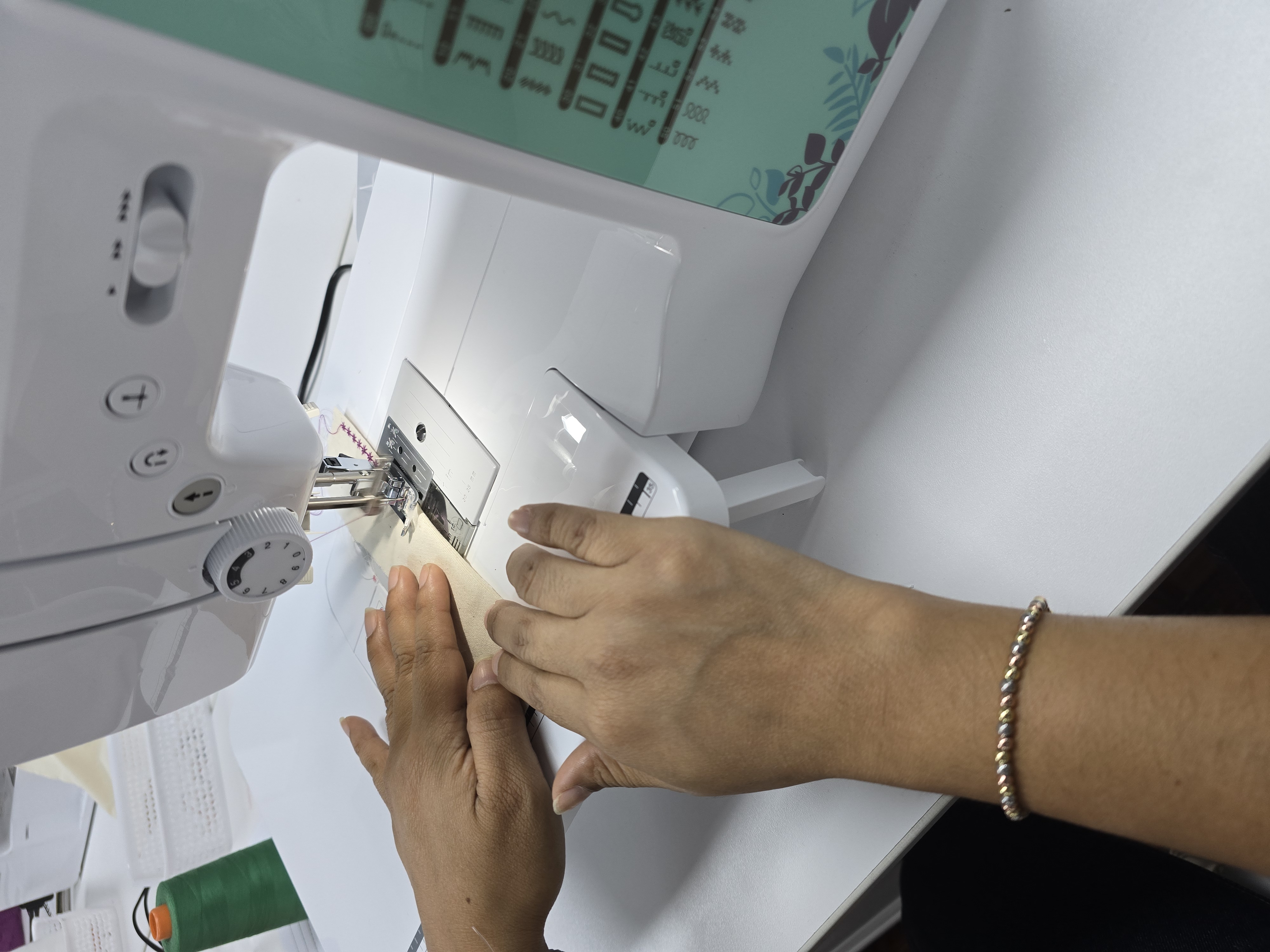 Manos de una alumna practicando en la máquina de coser