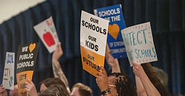 parents hold rally signs support funding for public schools