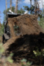 Man using a skid steer to turn a compost pile.