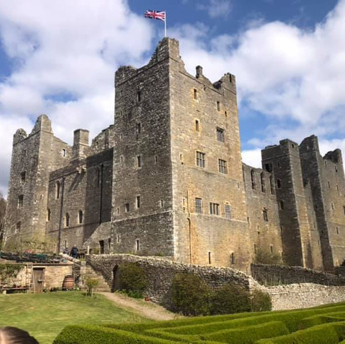Large stone castle with flag flying on a sunny day and green grass