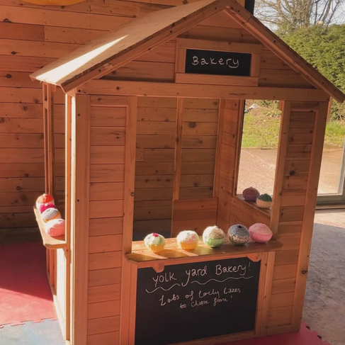 Wooden bakery stand with 'Bakery' sign and colorful toy treats inside