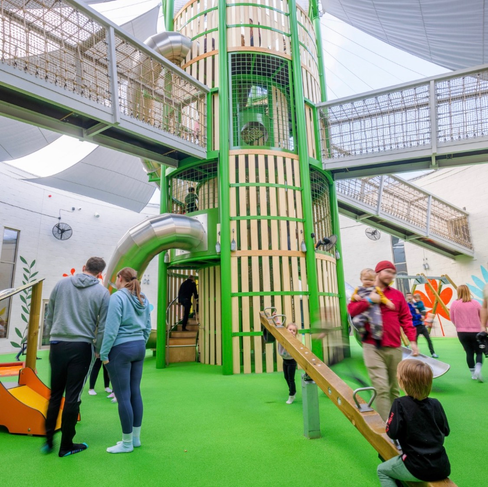 Kids playing at indoor playground with slides and structures, fun activities.