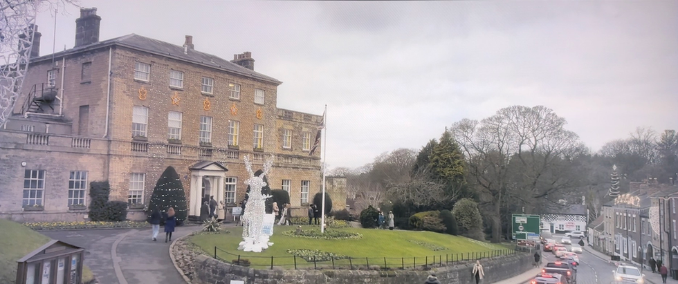 Exterior shot of a large Harrogate building with people and a statue.