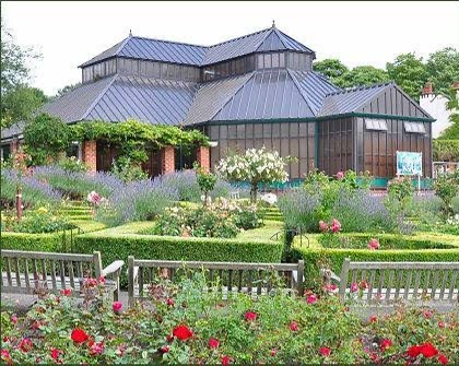 Elegant building surrounded by a beautiful garden with benches and flowers.