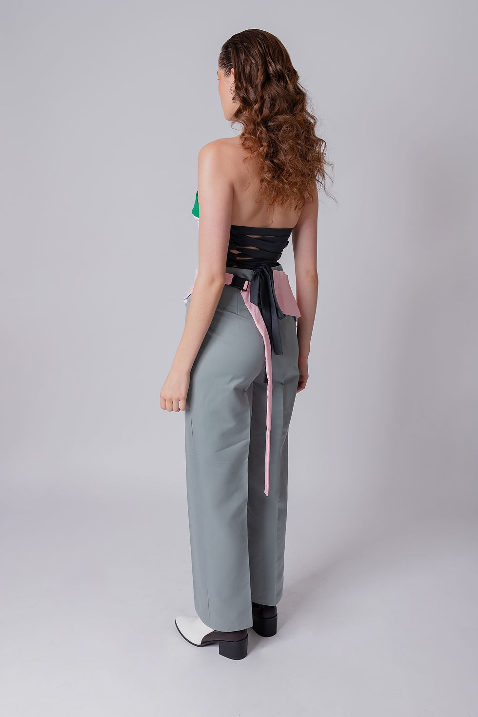 サムネイル： Pantalon droit gris avec poches cachées sur les côtés et ceinture avec pochette rose.