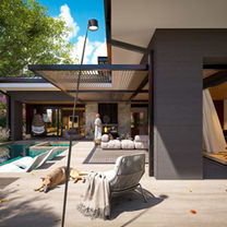Day image of the l-shaped single story home, featuring the courtyard configuration and lounge outdoor living area