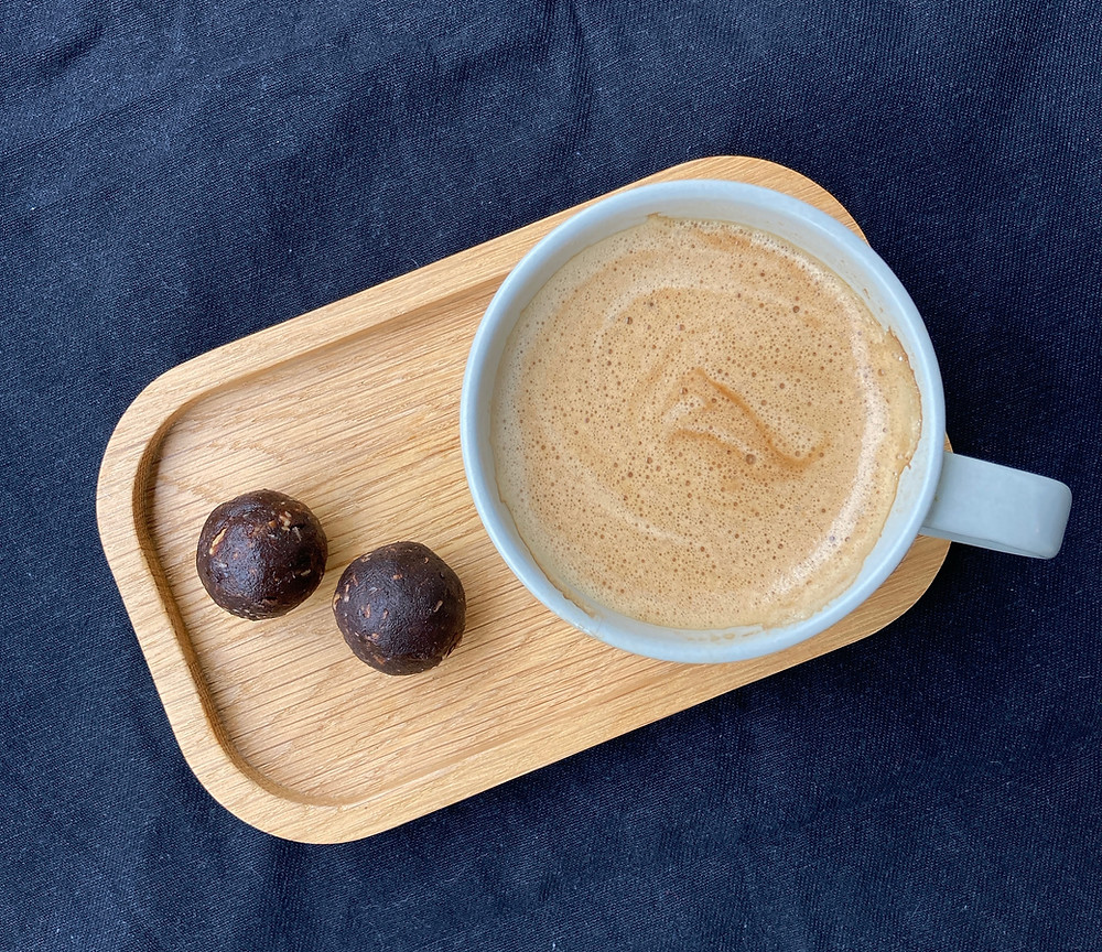 2 bliss balls on wooden tray with cup of coffee