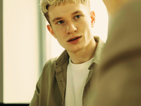 Focus on young man in a conversation. Other speaker is out of focus.