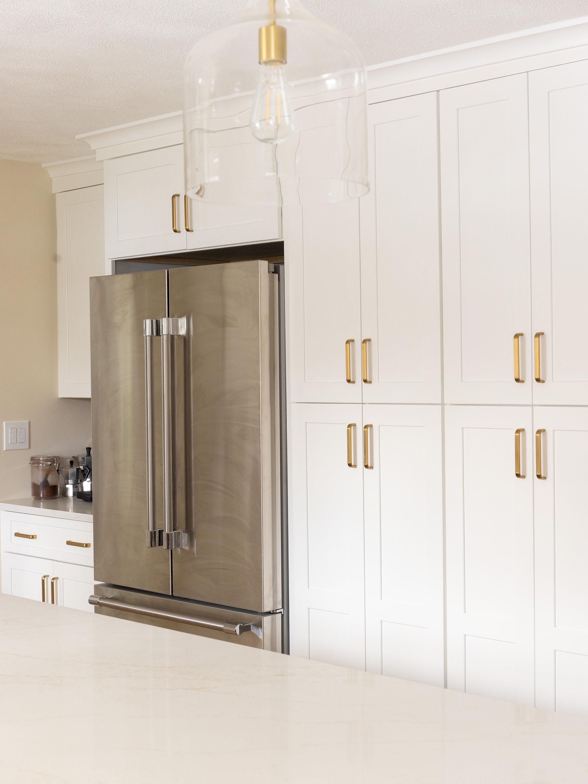 A kitchen with white cabinets and a stainless steel refrigerator.