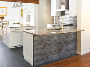 A kitchen with gray tile backsplash, quartz countertops, and white cabinets.