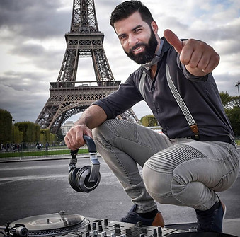 Dj souriant avec ses platines et son casquedevant la tour Eiffel