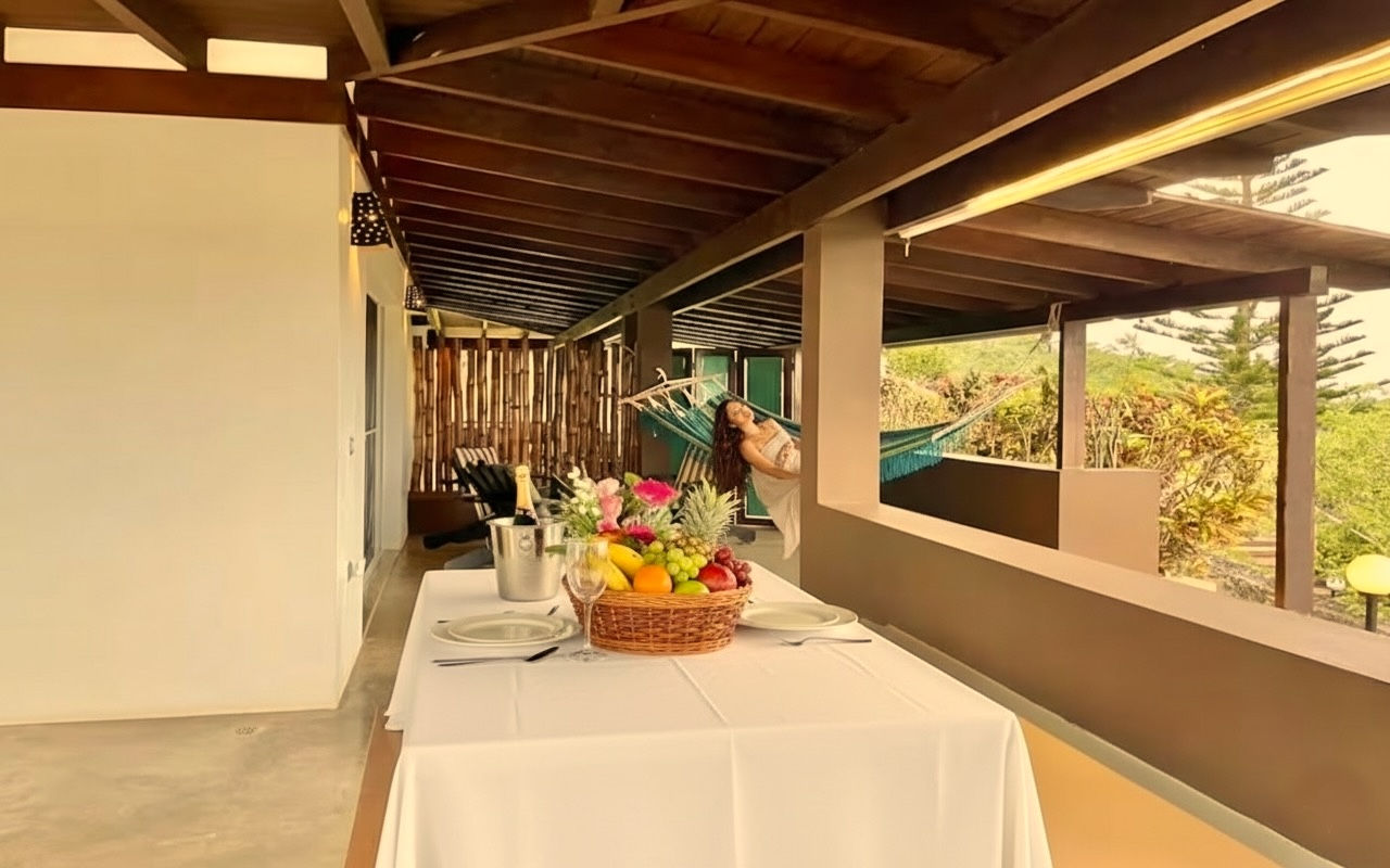 Guest relaxing in a hammock on a private suite terrace with tropical views and set dining table in Las Galeras.
