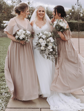 Bride with bridesmaids holding white rose floral bouquet