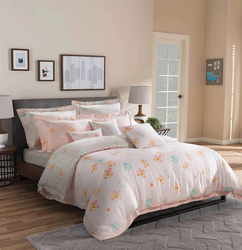 pink and floral pattern bed in a room with pink wall and wooden floor